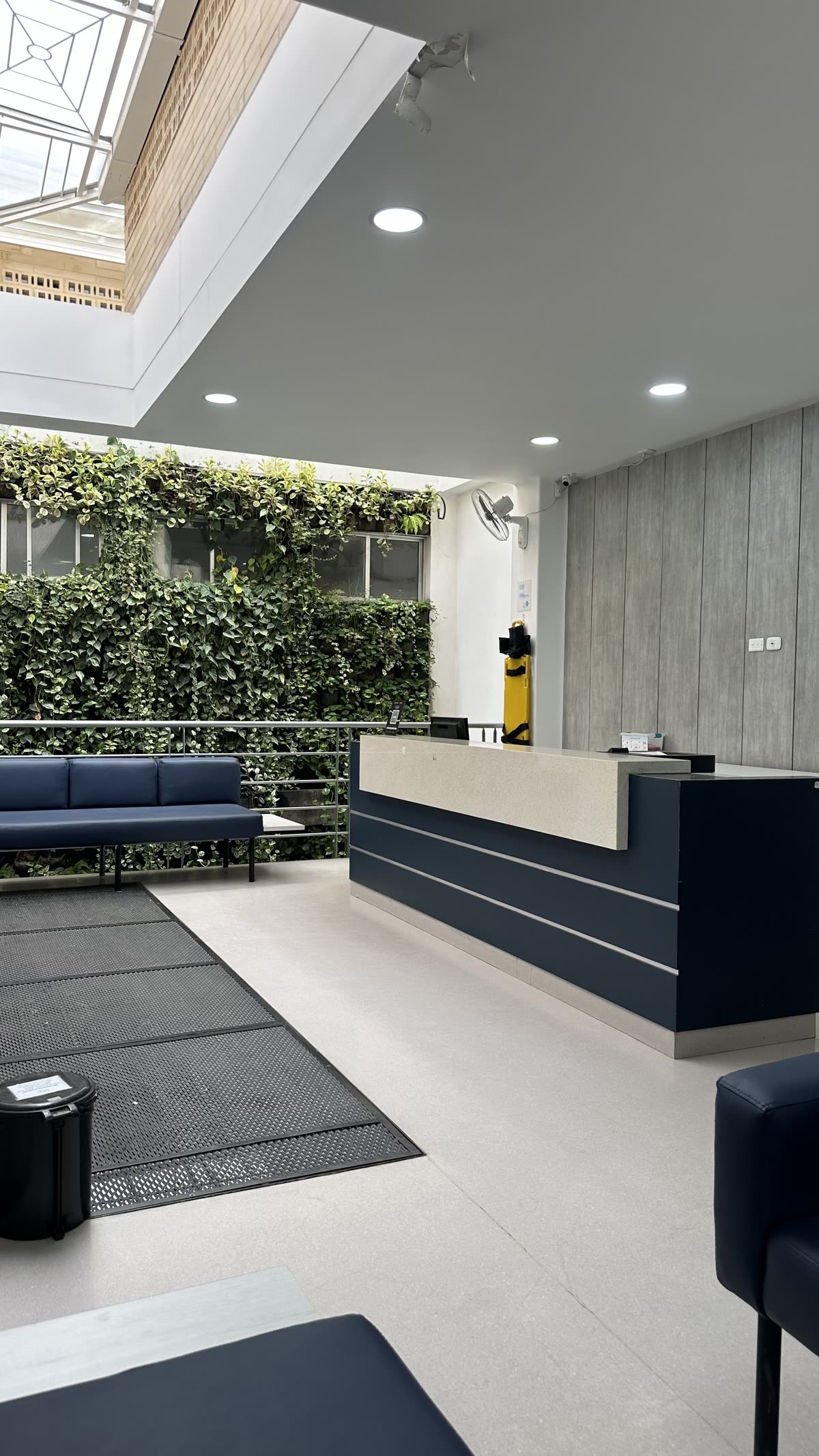 Sala de espera iluminada con luz natural junto a un jardín vertical.