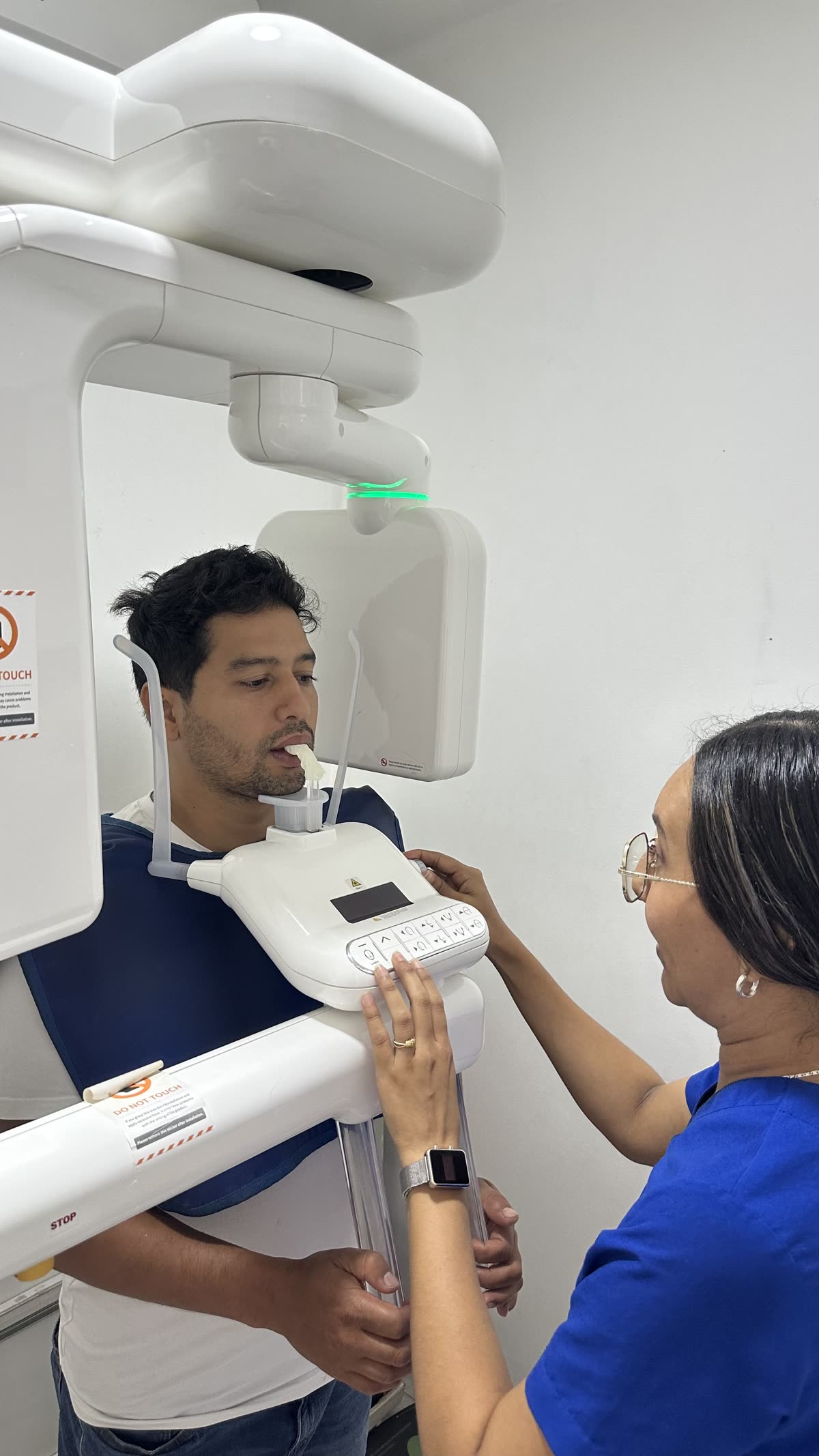 Auxiliar posicionando a un usuario en el equipo de radiografía panorámica dental.